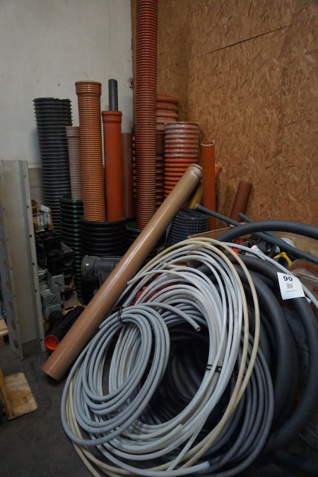 Indhold i hjørne af diverse PVC-kloakrør, slanger, fittings, mv.