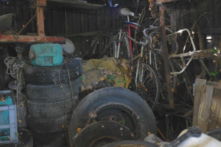 Shed content: oil barrels, bicycles, tires.