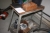 Arbejdsbord med skruestik og indhold, bl.a. rørfittings + stålreol med indhold i reol
