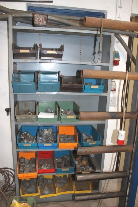 Rack containing various fittings + pipe clamps, etc.
