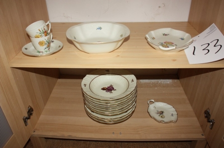 Parts of cheramic dinnerware on 2 shelves in closet, floral color