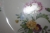 Parts of cheramic dinnerware on 2 shelves in closet, floral color