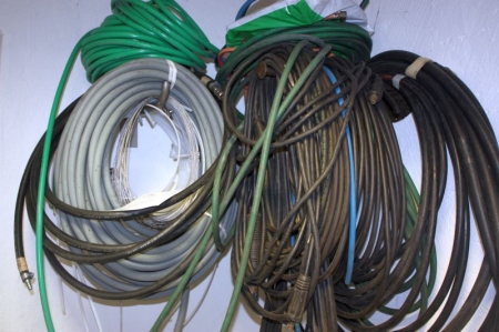 Various air hoses, welding hoses, power cables on wall