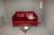 1 Stück. Zweisitziges Sofa in rot, 1 St. Couchtisch mit Glasplatte und einer Lampe.