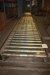 Drevet indkøringsrullebane for lager. Bredde = 1100 mm. Længde ca. 18000 mm. Inklusive løftebord for afsætning af paller med palleløfter samt styring