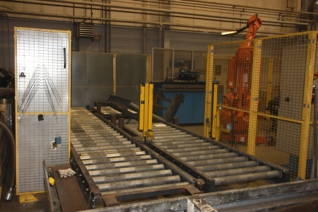 Pallet conveyor with driven rolls, tilt section and chain transfer, Skandow Machine. Year 1999. Length approx. 2 x 6.5 m spares for conviyor and  additional columns. Sick sensor system. Grid fence, Troax, with lattice shielding and noise barrier sections.