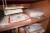 Contents in 3 compartment shelf of various sanding paper, hearing protection, filter, painter's suits, etc.